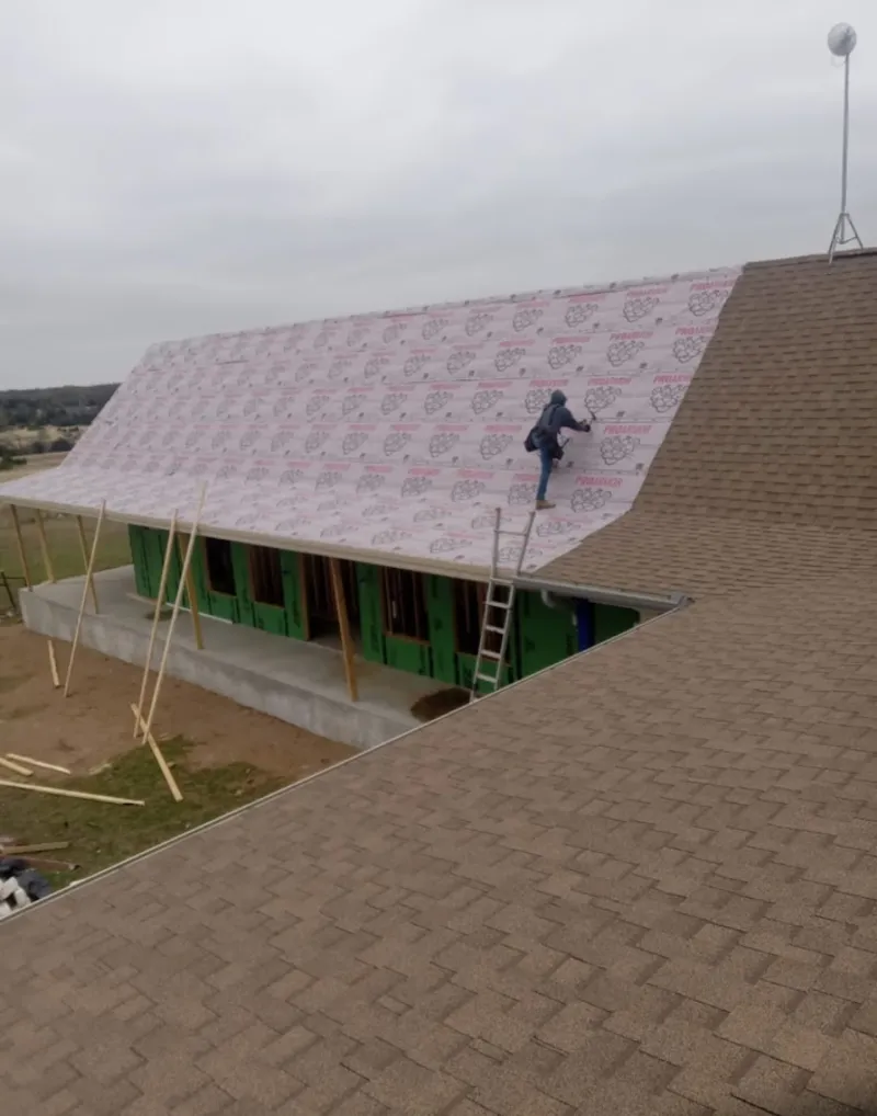 Worker preparing underlayment for a metal roof installation in Fair Haven